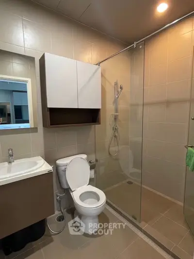 Modern bathroom with glass shower and sleek fixtures in contemporary apartment.