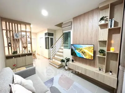Modern living room with stylish wooden paneling and built-in TV unit, featuring cozy seating and decorative shelving.