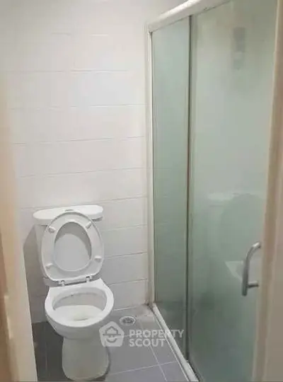Compact bathroom with shower and toilet in modern apartment.