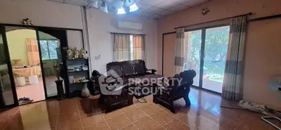 Spacious living room with traditional wooden furniture and large sliding glass doors opening to a garden view.