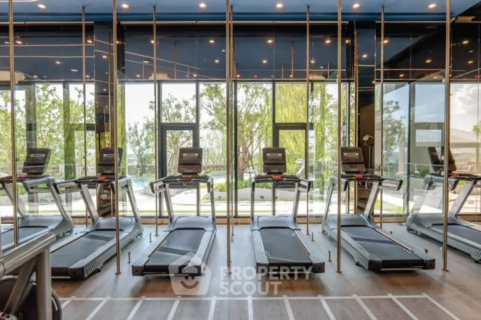 Modern gym with treadmills and large windows overlooking greenery