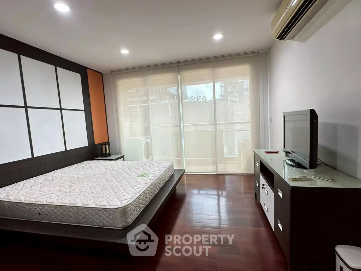 Spacious bedroom with modern decor and large windows leading to a balcony.