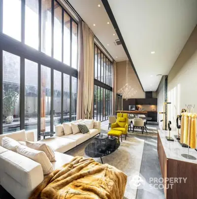 Luxurious modern living room with high ceilings and large windows, open to a stylish kitchen.