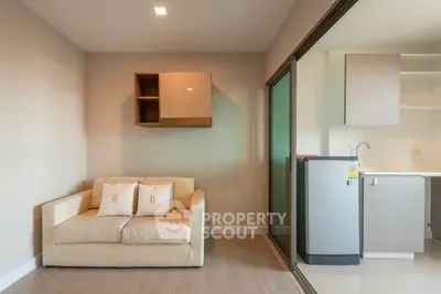 Modern living room with cozy sofa and compact kitchen in open layout apartment.