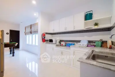 Spacious kitchen with modern appliances and ample storage, adjacent to a game room with pool table.