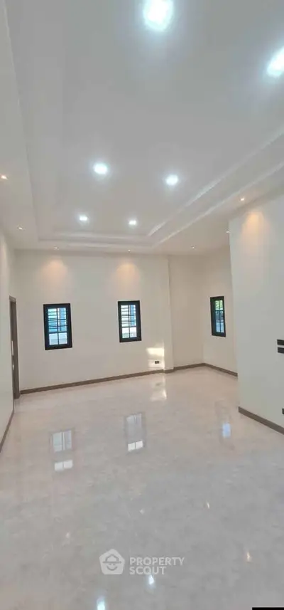 Spacious modern living room with elegant lighting and tiled flooring, perfect for family gatherings.