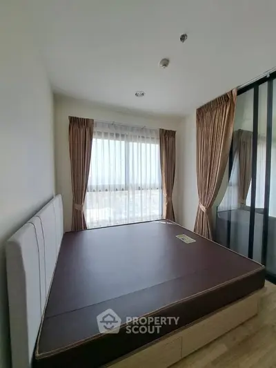 Spacious bedroom with large windows and elegant curtains, offering a serene and bright atmosphere.