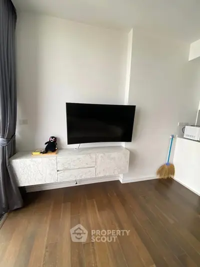 Modern living room with wall-mounted TV and stylish cabinet on wooden flooring.