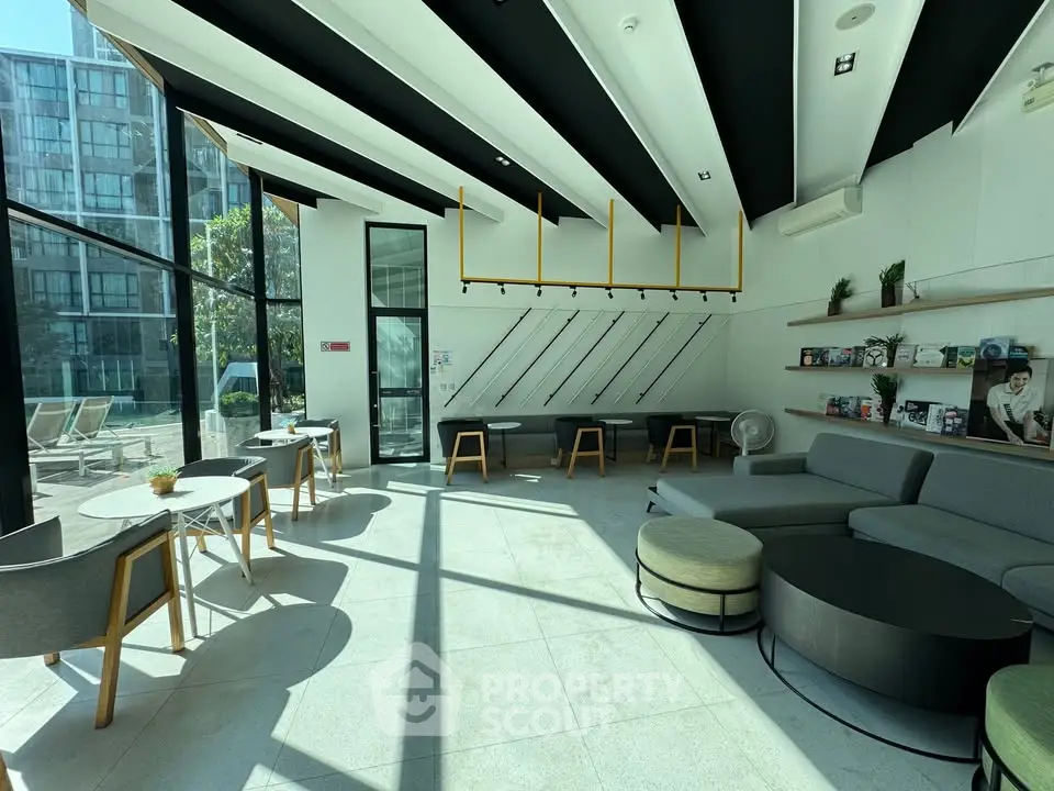 Modern co-working space with stylish seating and large windows in a contemporary building.