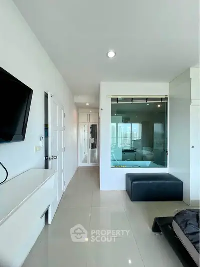 Modern bedroom with glass partition and city view, featuring sleek design and natural light.
