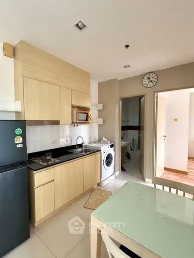 Modern kitchen with washing machine and sleek cabinetry in a cozy apartment setting.