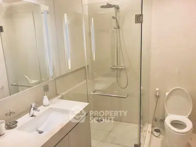 Modern bathroom with glass shower and sleek fixtures in luxury apartment.