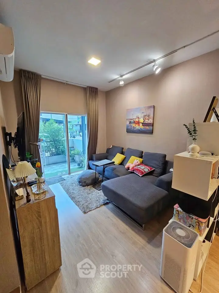 Cozy living room with modern decor and large window overlooking greenery.