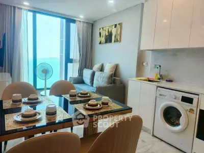 Modern living room with ocean view, dining area, and washing machine