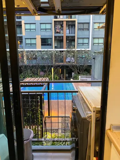 Charming balcony view overlooking a modern pool in a stylish apartment complex.