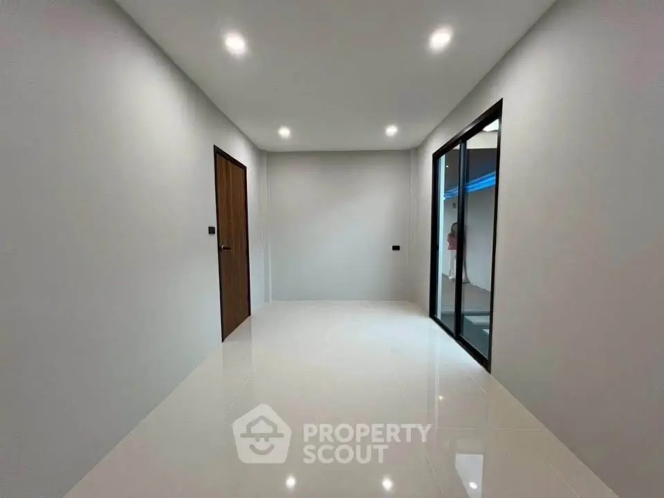 Spacious modern room with glossy white tiles and wooden door
