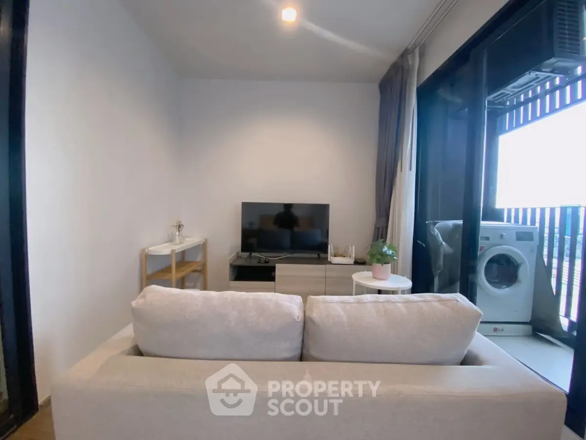 Cozy living room with modern decor and balcony view featuring washing machine.