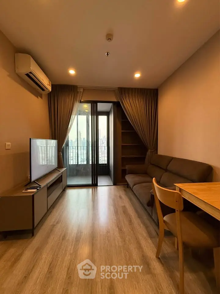 Modern living room with city view, featuring sleek furniture and wooden flooring.