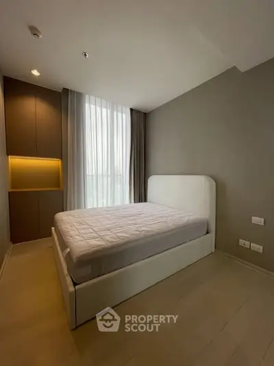 Modern bedroom with minimalist design and large window for natural light.