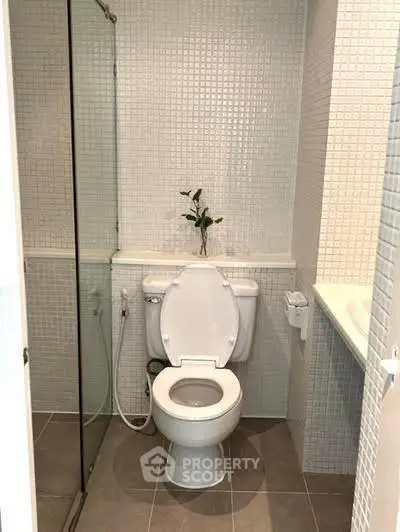 Modern bathroom with sleek design and tiled walls, featuring a toilet and shower area.