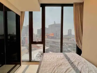 Modern bedroom with large windows offering a stunning city view, perfect for urban living.