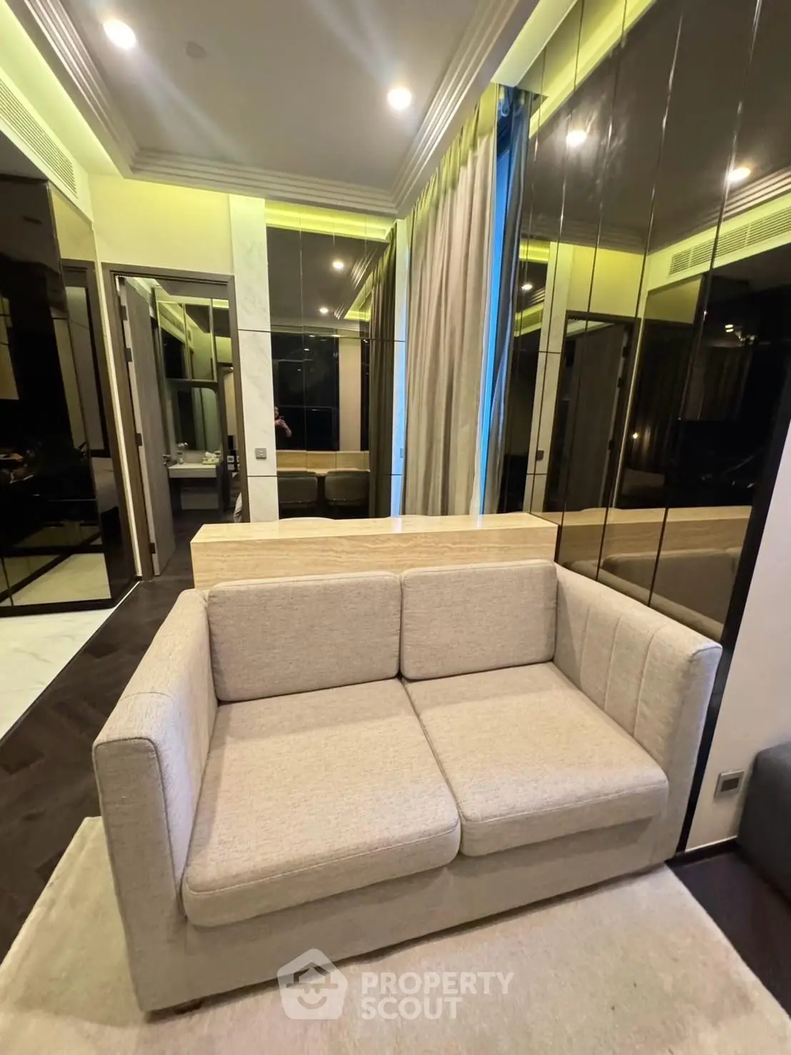 Modern living room with stylish sofa and mirrored wall accents in a luxurious apartment.