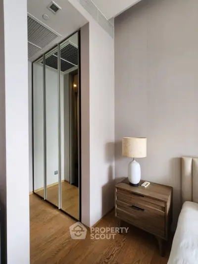 Modern bedroom with mirrored closet and stylish wooden nightstand
