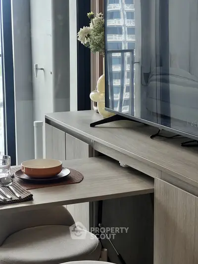 Modern living room with sleek TV stand and dining setup, featuring elegant decor and natural light.