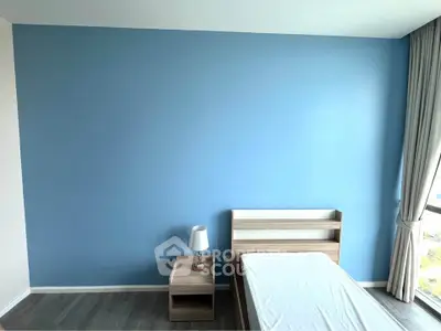 Modern minimalist bedroom with blue accent wall and natural light