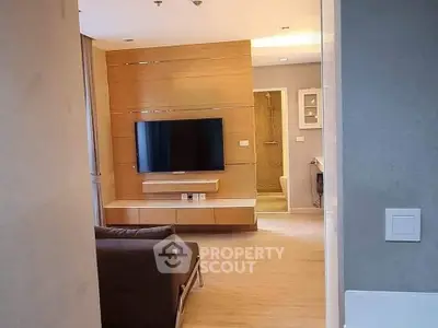 Modern living room with sleek wooden paneling and wall-mounted TV, leading to a stylish bathroom.