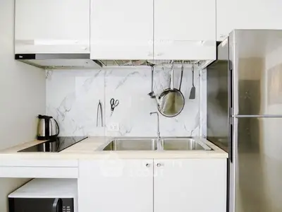 Modern kitchen with sleek appliances and marble backsplash, featuring a stainless steel fridge and electric stove.