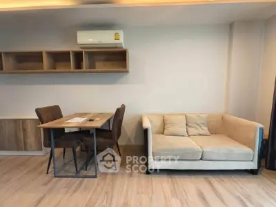 Modern living room with cozy sofa and dining table, featuring sleek wooden flooring and wall-mounted shelves.
