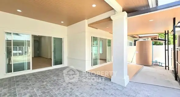 Spacious modern patio with sliding glass doors and tiled flooring in a contemporary home.
