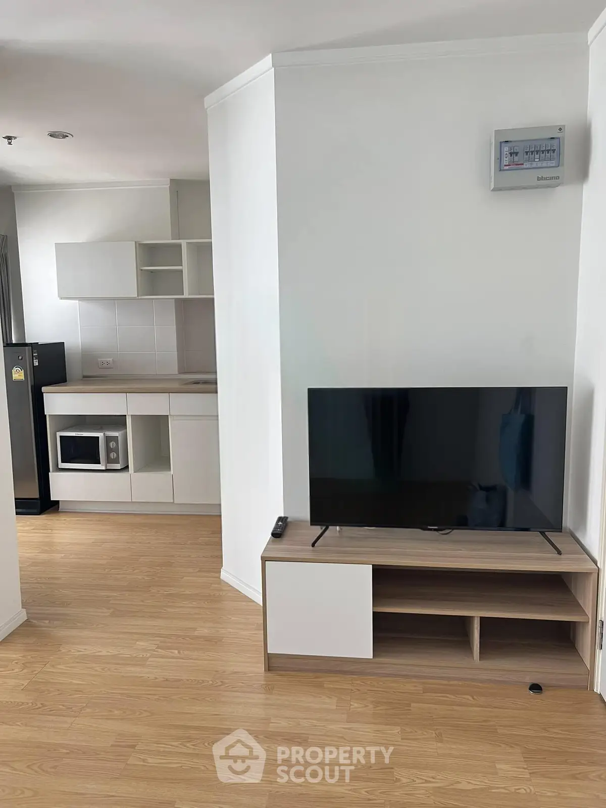 Modern apartment interior with sleek kitchen and cozy living area featuring a flat-screen TV.