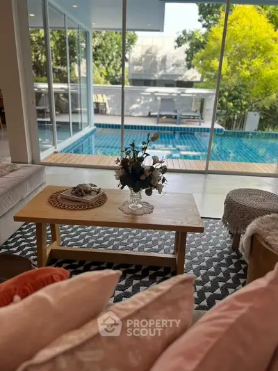 Luxurious living room with pool view, elegant decor, and abundant natural light.
