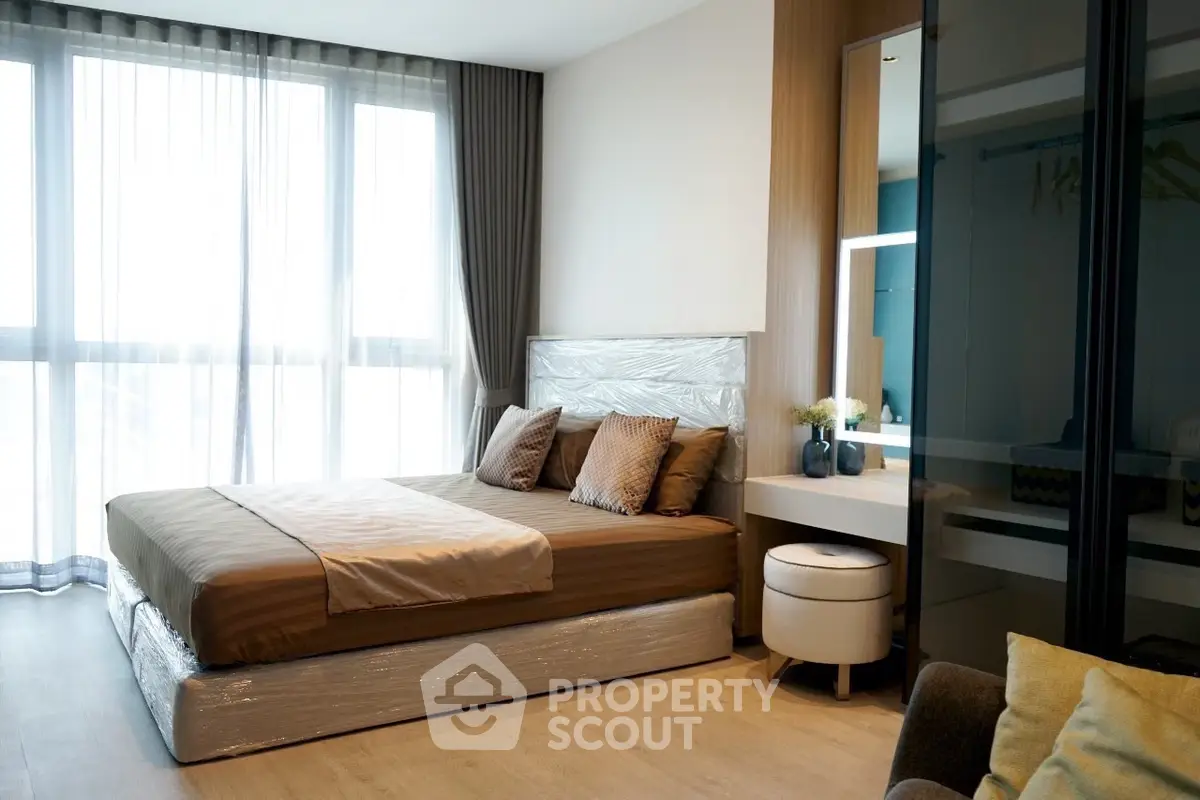 Modern bedroom with large windows, stylish decor, and natural light.