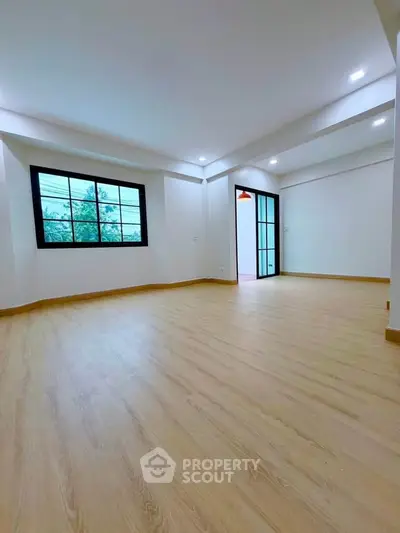 Spacious empty living room with large window and wooden flooring