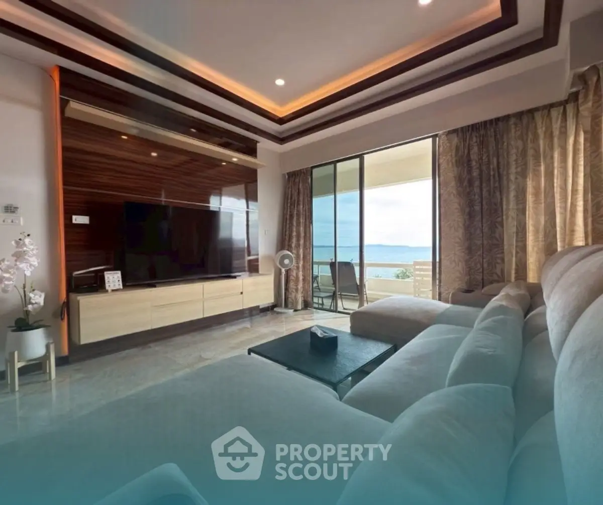 Luxurious living room with ocean view and modern decor, featuring a large TV and comfortable seating.