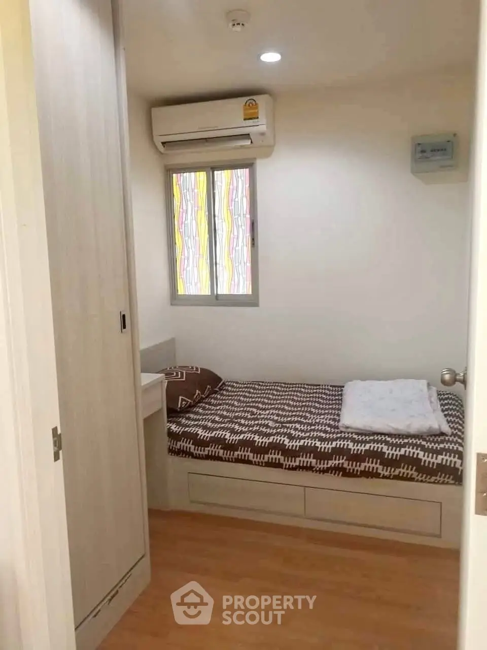 Cozy small bedroom with single bed and air conditioning in modern apartment.