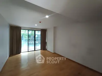 Spacious empty room with large windows and wooden flooring, ideal for customization.