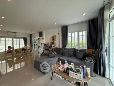 Spacious modern living room with large windows and stylish gray sofa