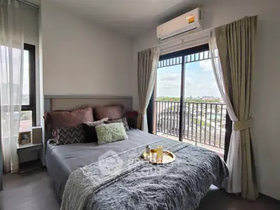 Cozy bedroom with balcony view, featuring stylish decor and natural light, perfect for relaxation.