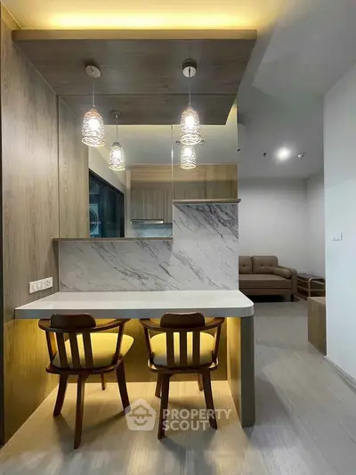 Modern open-layout kitchen with stylish lighting and cozy seating area in a contemporary apartment.