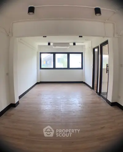 Spacious empty room with large windows and wooden flooring, ideal for customization.