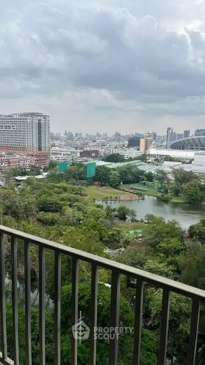 Stunning cityscape view from a high-rise balcony overlooking lush greenery and urban skyline.