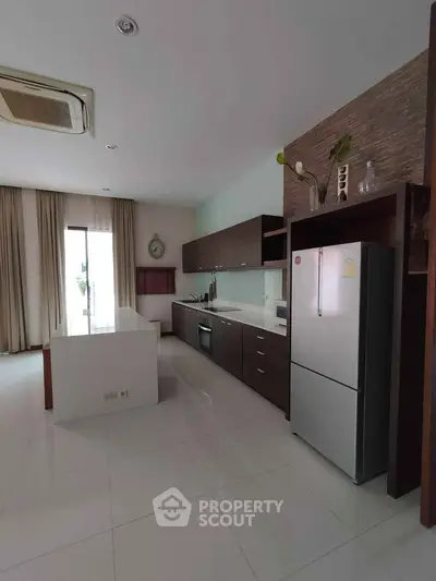 Spacious modern kitchen with sleek cabinetry and large fridge in a bright open layout.