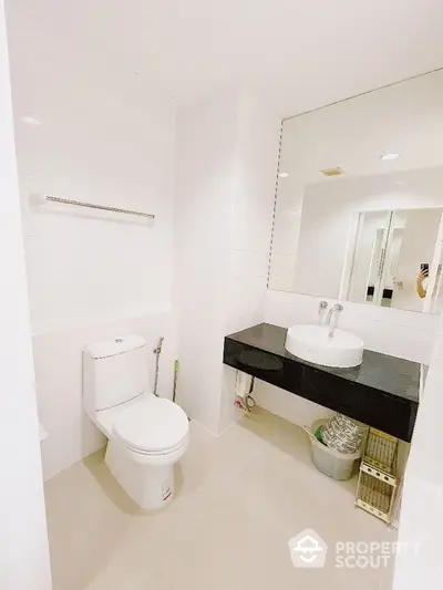 Pristine white bathroom with modern fixtures, large mirror, and sleek vanity offering a clean and refreshing space in a contemporary home.