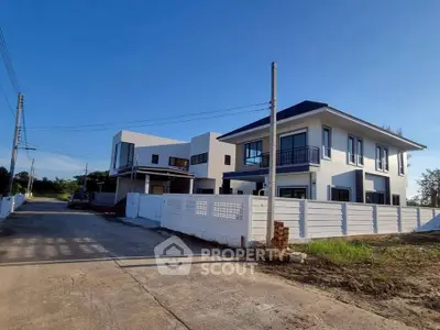 Modern two-story house with white fence and spacious driveway in a serene neighborhood.