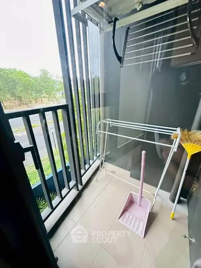 Compact balcony with cleaning tools and outdoor view, ideal for small apartments.