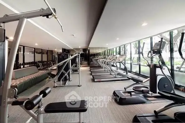 Spacious modern gym with state-of-the-art equipment and large windows offering garden views.